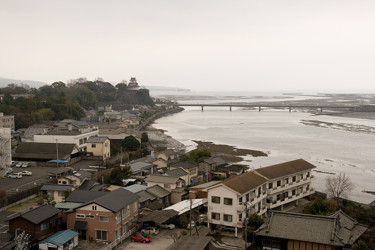 Looking down over the rooftops of Kitsuki towards the river mouth, with the small castle keep visible on the wooded hill at the left