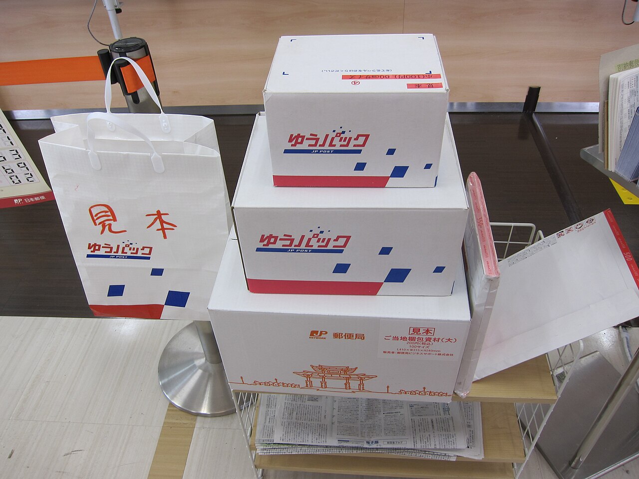 Stacked Japan Post Yu-Pack parcel boxes and a sample bag on display at a post office counter