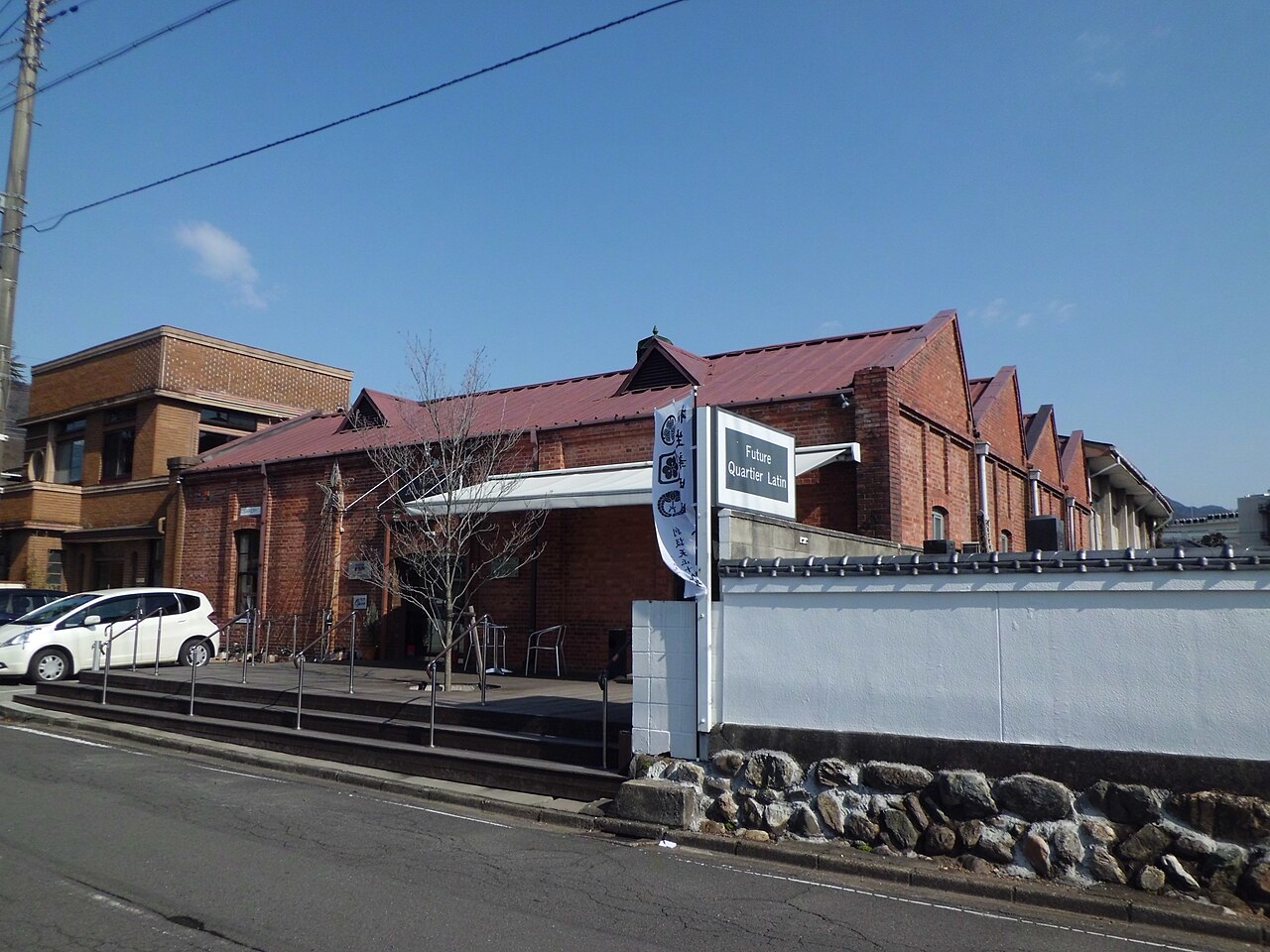 A red-brick former weaving shed with a row of sawtooth roof gables, now home to a bakery cafe, in Kiryu.