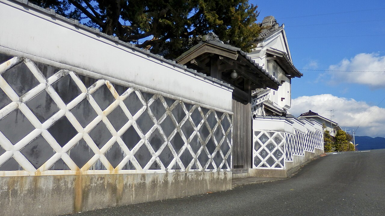 Namako-kabe walls and a tiled gate on a street in Matsuzaki