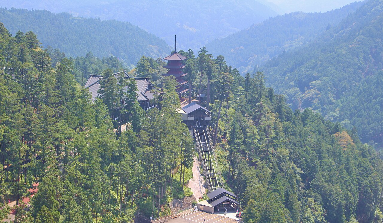 View over forested hills showing the pagoda and the long stone stairway at Kuon-ji
