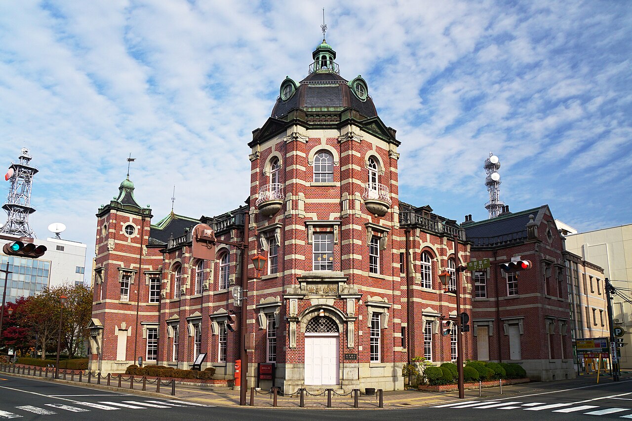 The red-brick Iwate Bank Red Brick Building (the former Morioka Bank Head Office) with its domed tower, seen from the street corner under a partly cloudy sky.