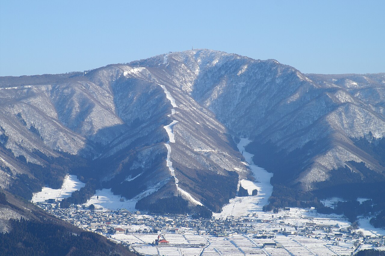 Mount Kenashi with ski runs above Nozawa Onsen village in winter, seen from across the valley