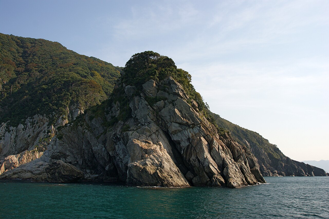 Rocky headland covered in trees on the Sotomo coast near Obama, seen from the sea