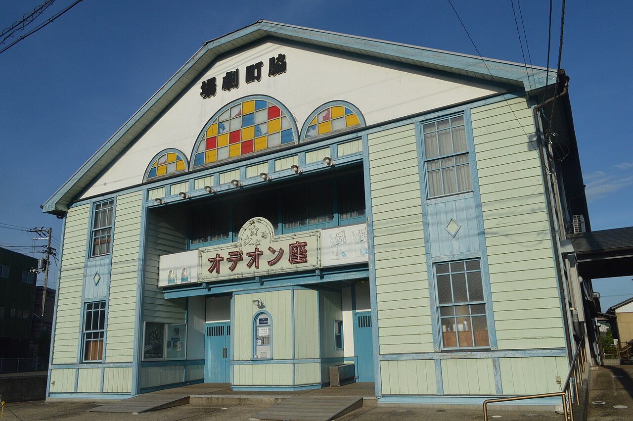 The pastel green and blue wooden facade of the Odeon-za theater in Wakimachi, with a stained-glass fan window above the entrance and a sign reading Odeon-za.