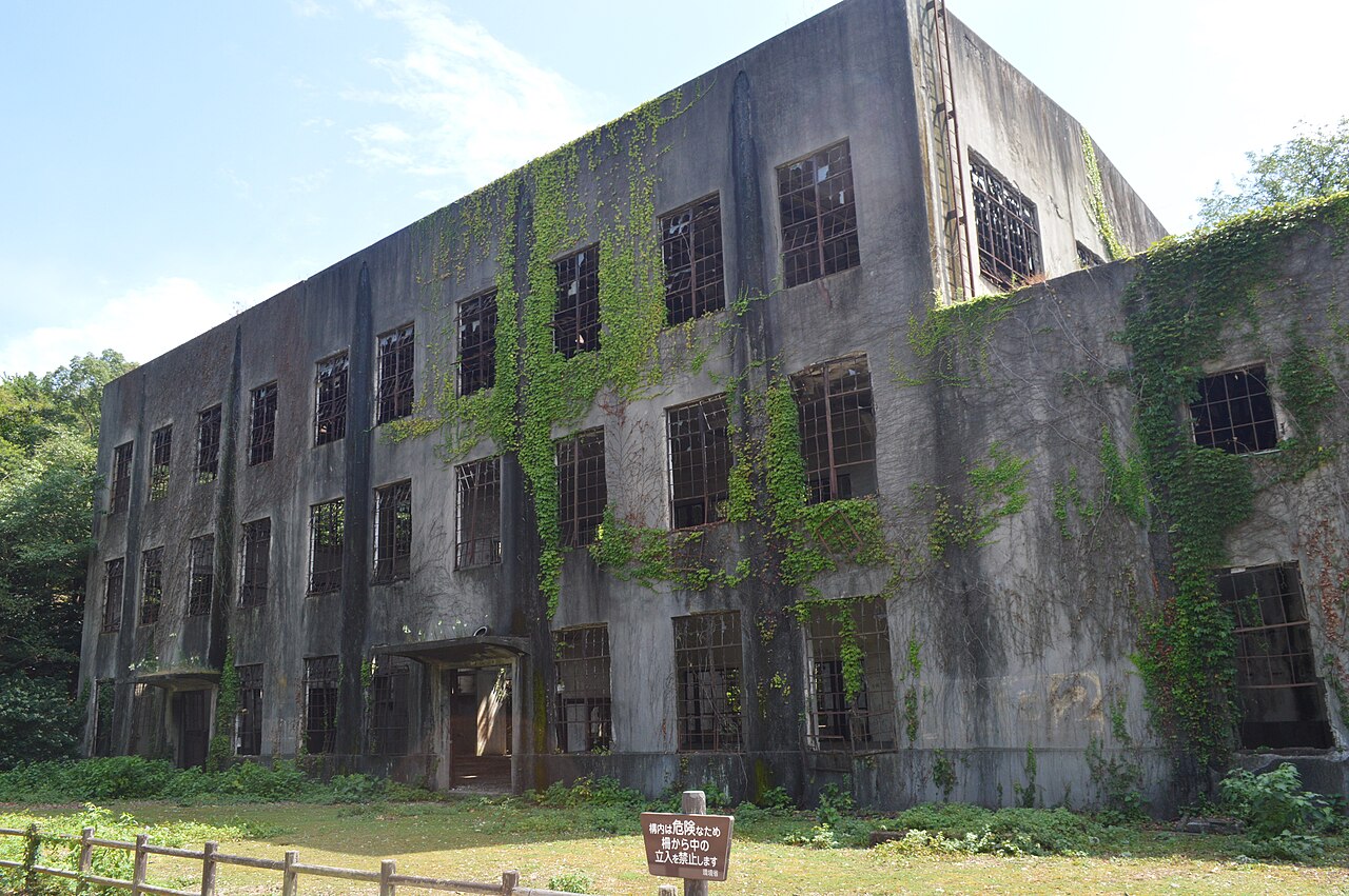 A three-storey concrete power plant ruin on Okunoshima, its windows empty and ivy climbing the walls.
