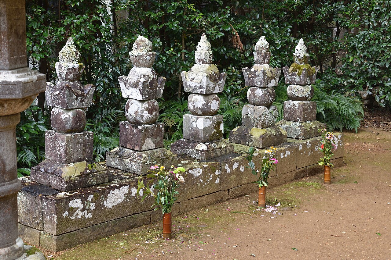 Five moss-covered stone grave markers of the Ii clan in a row at Ryotanji Temple