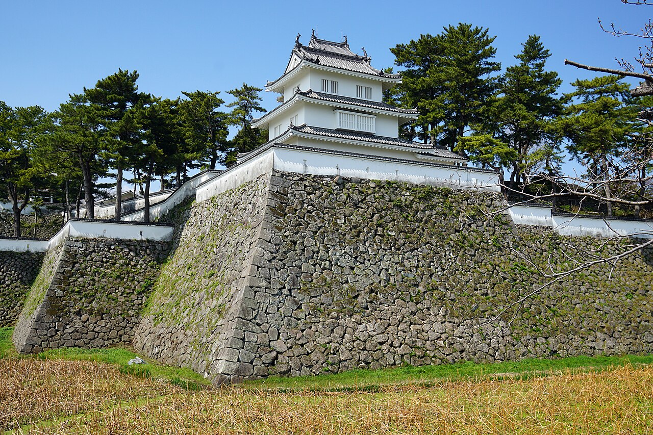 The white multi-tiered tower of Shimabara Castle rising above its stone walls
