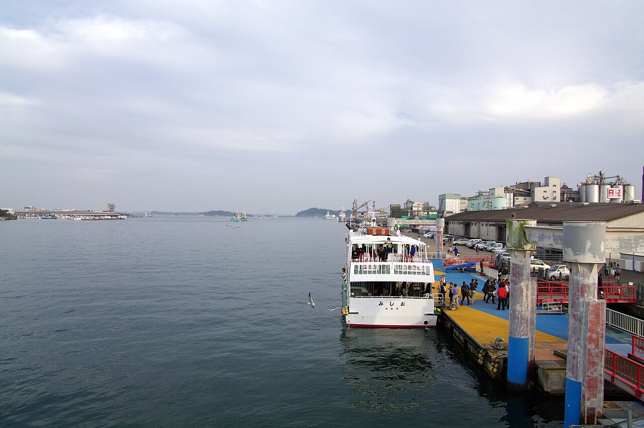 A tour boat moored at the Marine Gate Shiogama pier with the bay and the town beyond