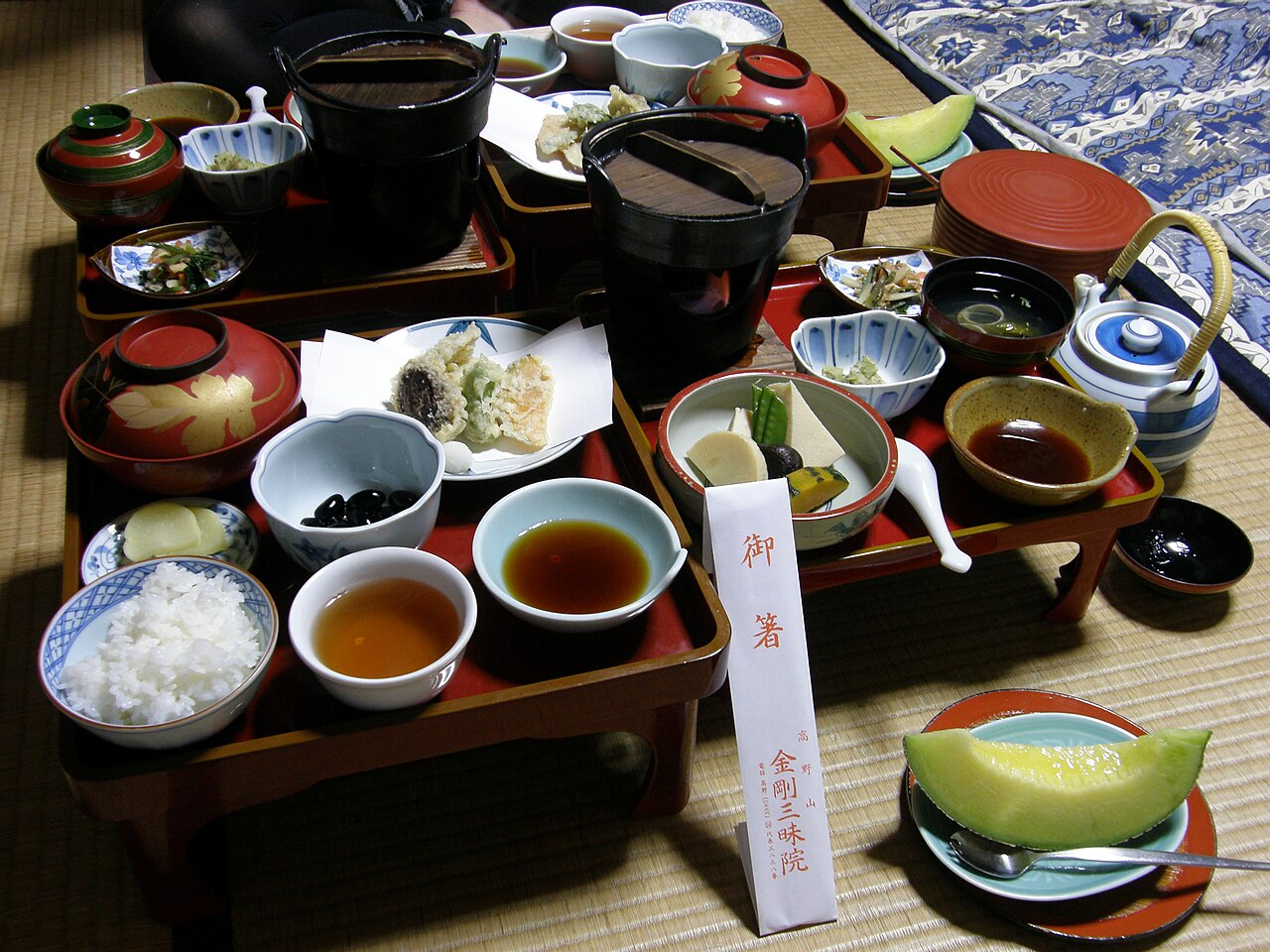 A shojin ryori vegetarian dinner on red lacquered trays at Kongo Sanmai-in, a temple lodging on Koyasan, with rice, tempura, soup and melon