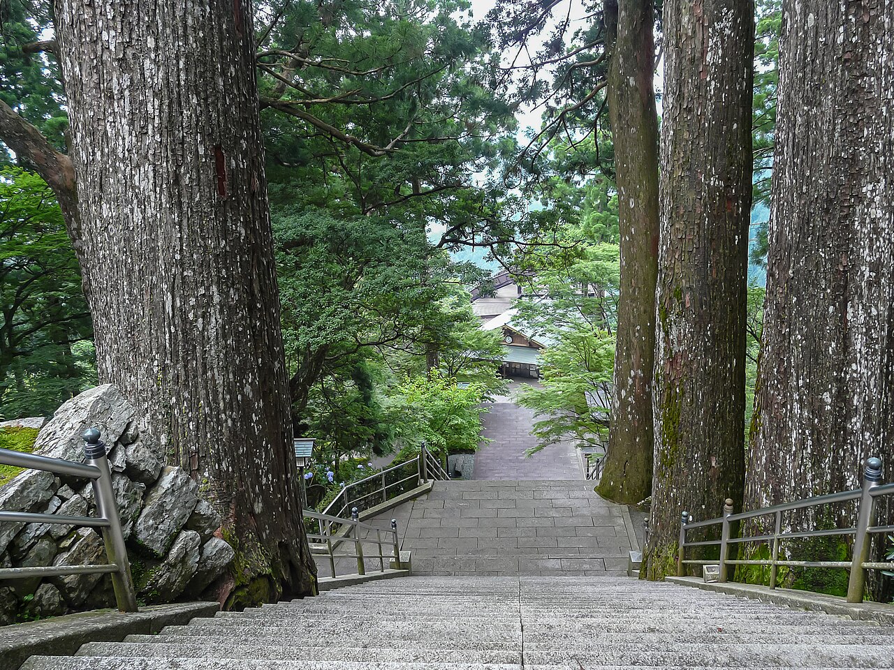 A stone staircase on the approach to Tairyuji running between tall cedar trees