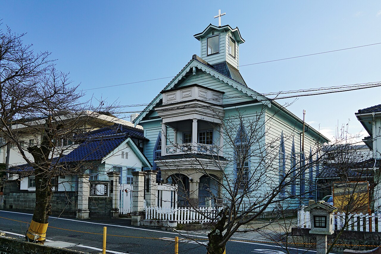 The pale blue wooden Takahashi Christ Church with a small bell tower, seen from the street in Takahashi