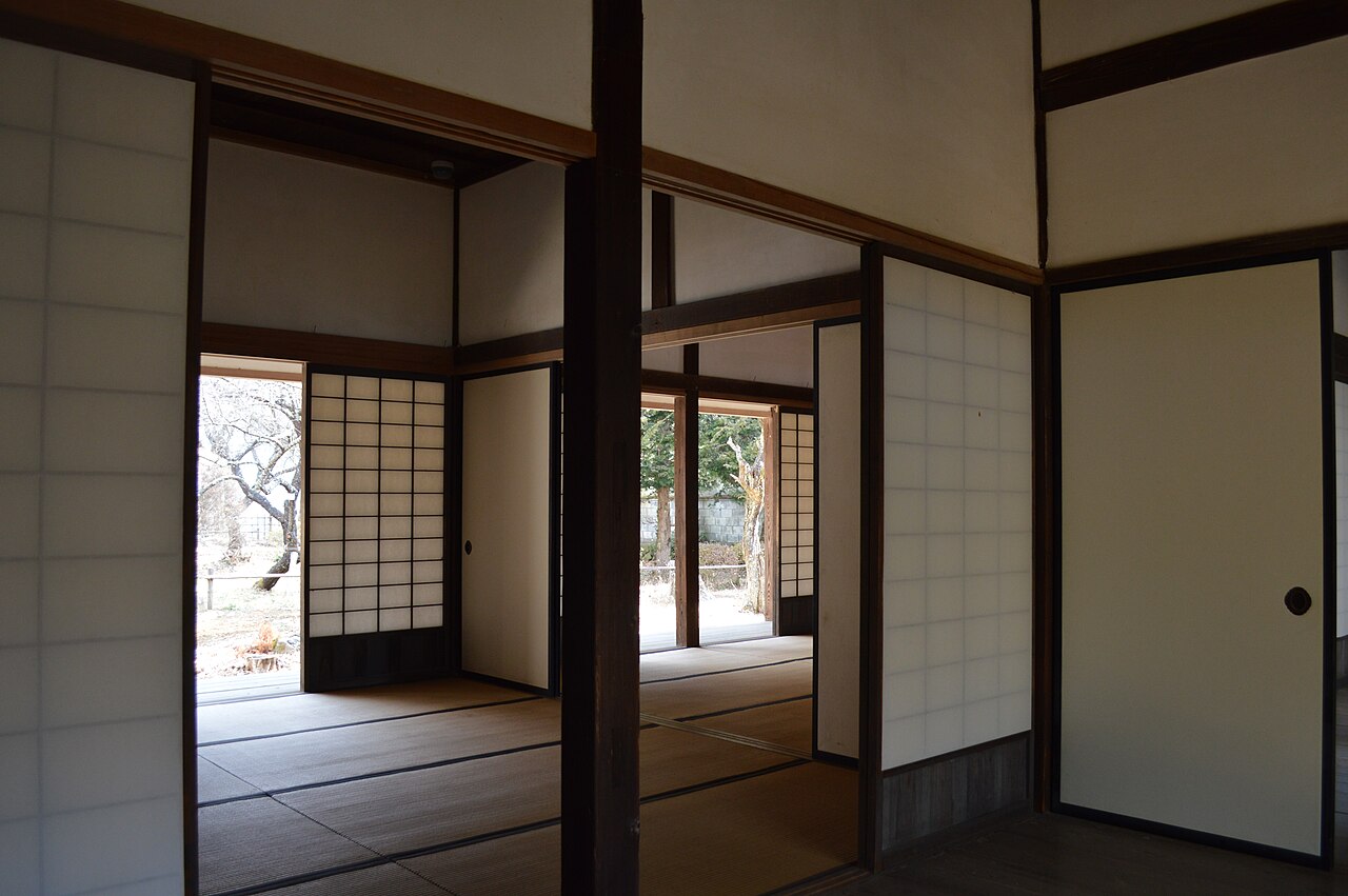 Interior of the Shintokukan domain school in Takato, with tatami rooms divided by paper sliding doors and bare winter trees visible through the open doorways.