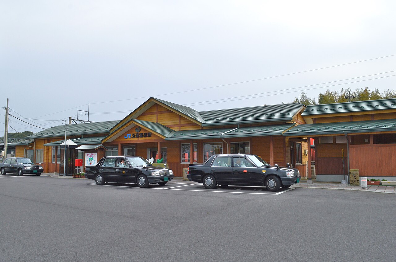 Black taxis parked in front of a low wooden station building at a hot spring town