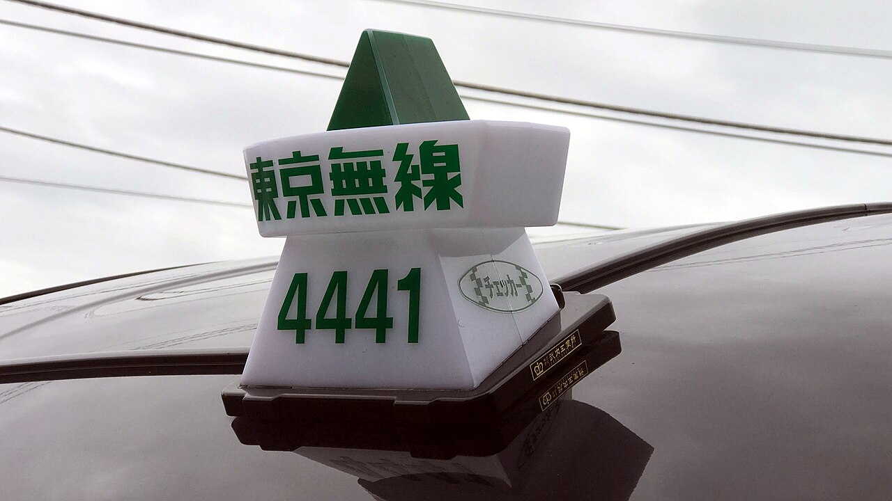 Close-up of a taxi roof lamp showing the company name and a four-digit car number
