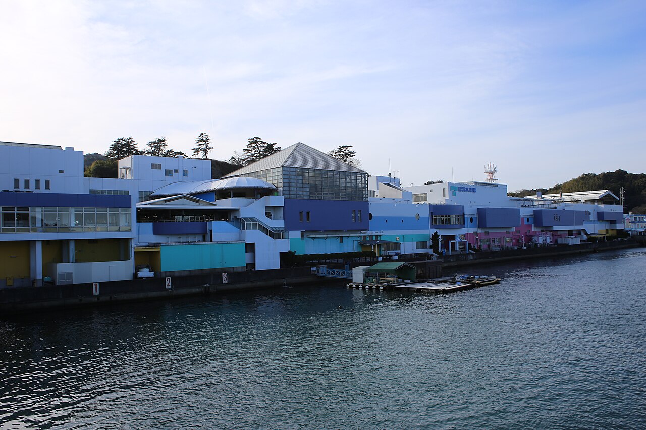 The colourful pastel exterior of Toba Aquarium on the waterfront with palm trees in front