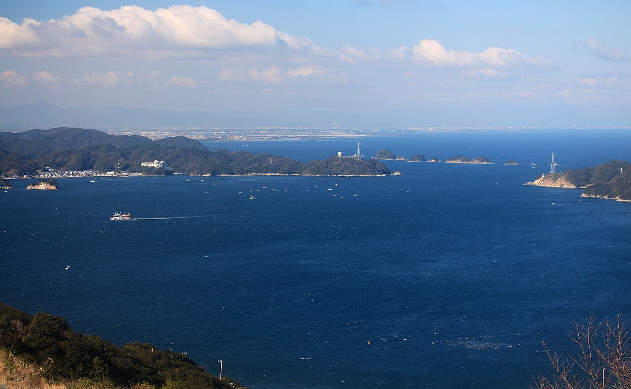 A wide view over the deep blue water of Toba Bay with layered hills and distant islands on the horizon