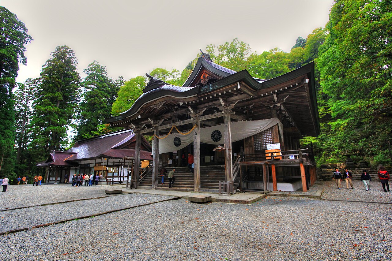 Wide wooden hall of Togakushi Shrine Chusha with a carved gabled front, set behind a gravel forecourt among tall trees