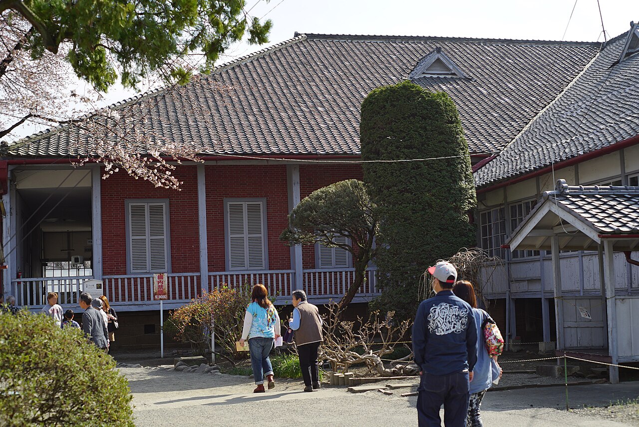 The Brunat House at Tomioka Silk Mill, with its tiled roof and raised veranda, and visitors walking in the front garden