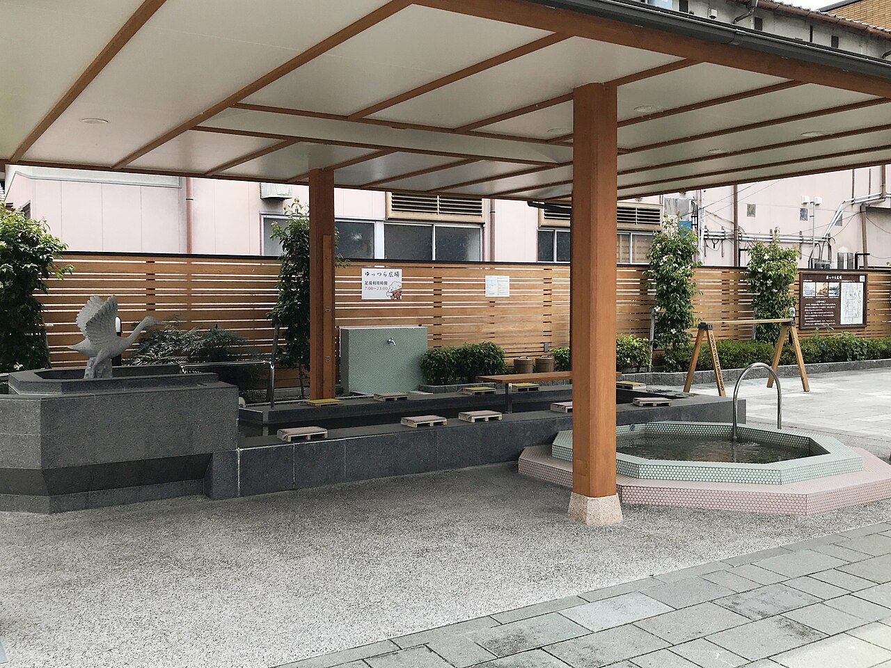 Covered footbath at Yuttsura Square in Ureshino Onsen, with stone basins, small wooden footrests and a timber roof