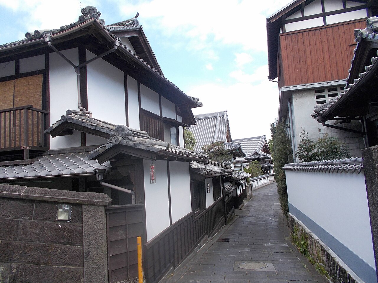 A quiet stone-paved lane lined with old temple walls in the Nioza district of Usuki