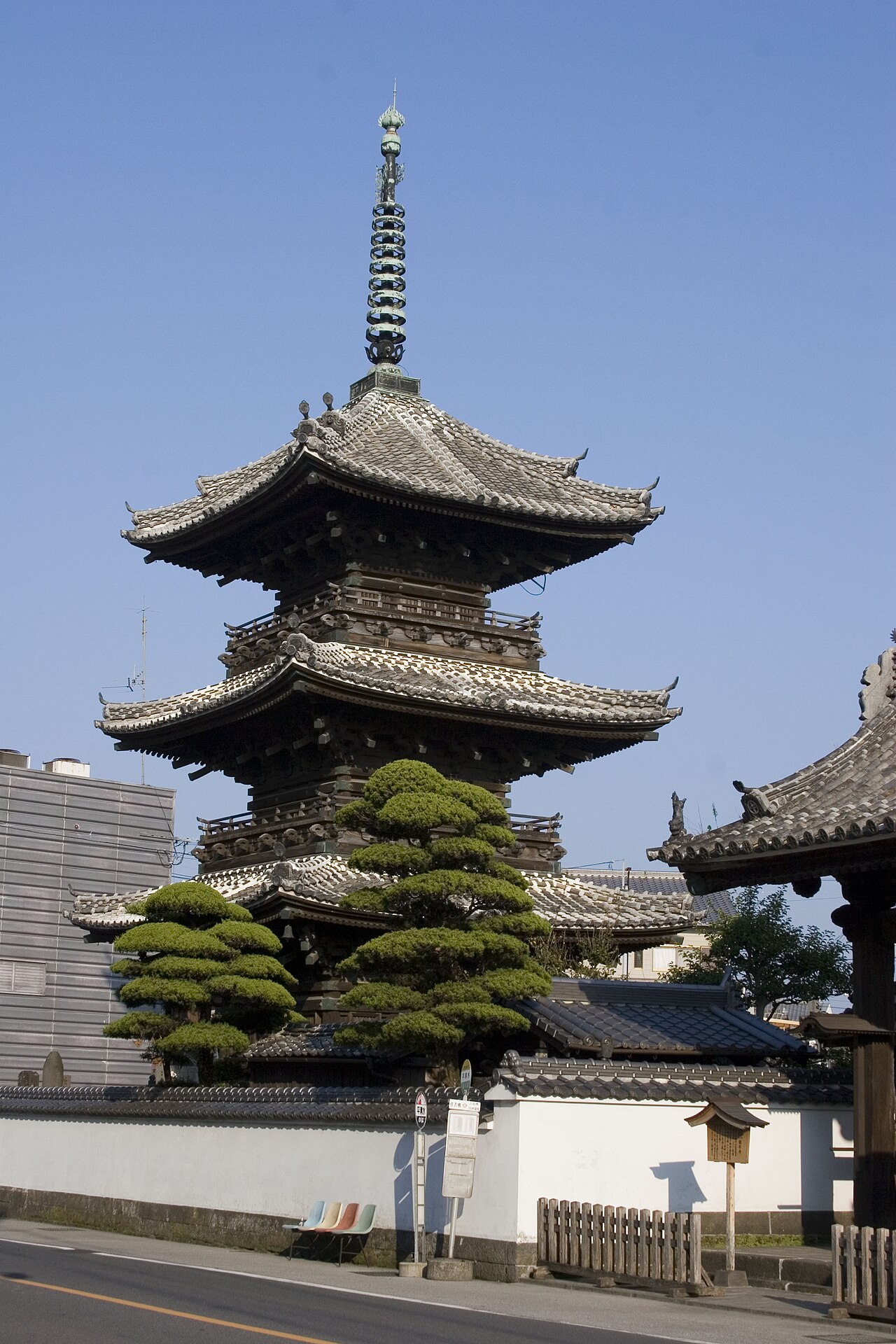 A wooden three-story pagoda rising above trees at Ryugenji Temple in Usuki