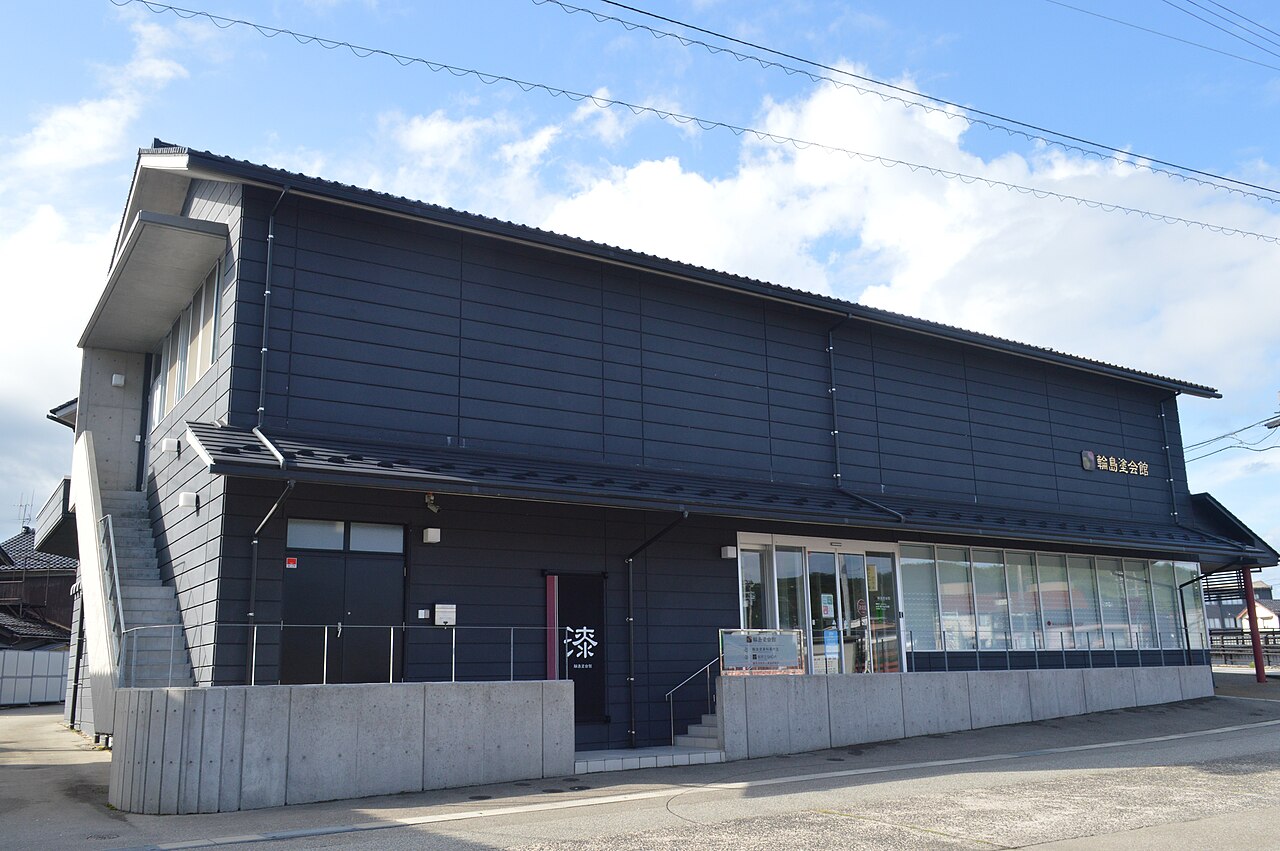 The Wajima Lacquerware Hall, a dark two-storey building under a blue sky