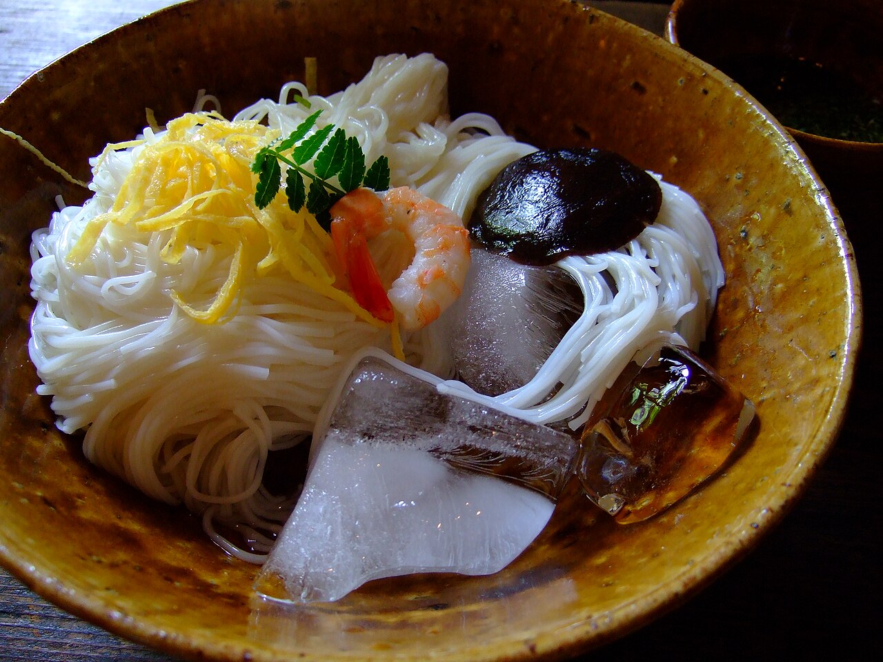 Bowl of cold Miwa somen with thin white noodles, shredded egg, shrimp, mushroom and ice cubes
