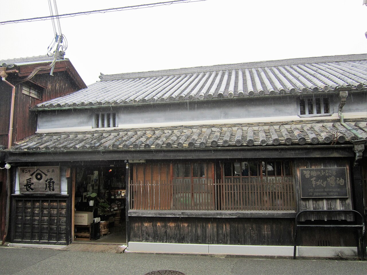 Front of an old wooden shop with a tiled roof, lattice windows and a hanging signboard in Yuasa