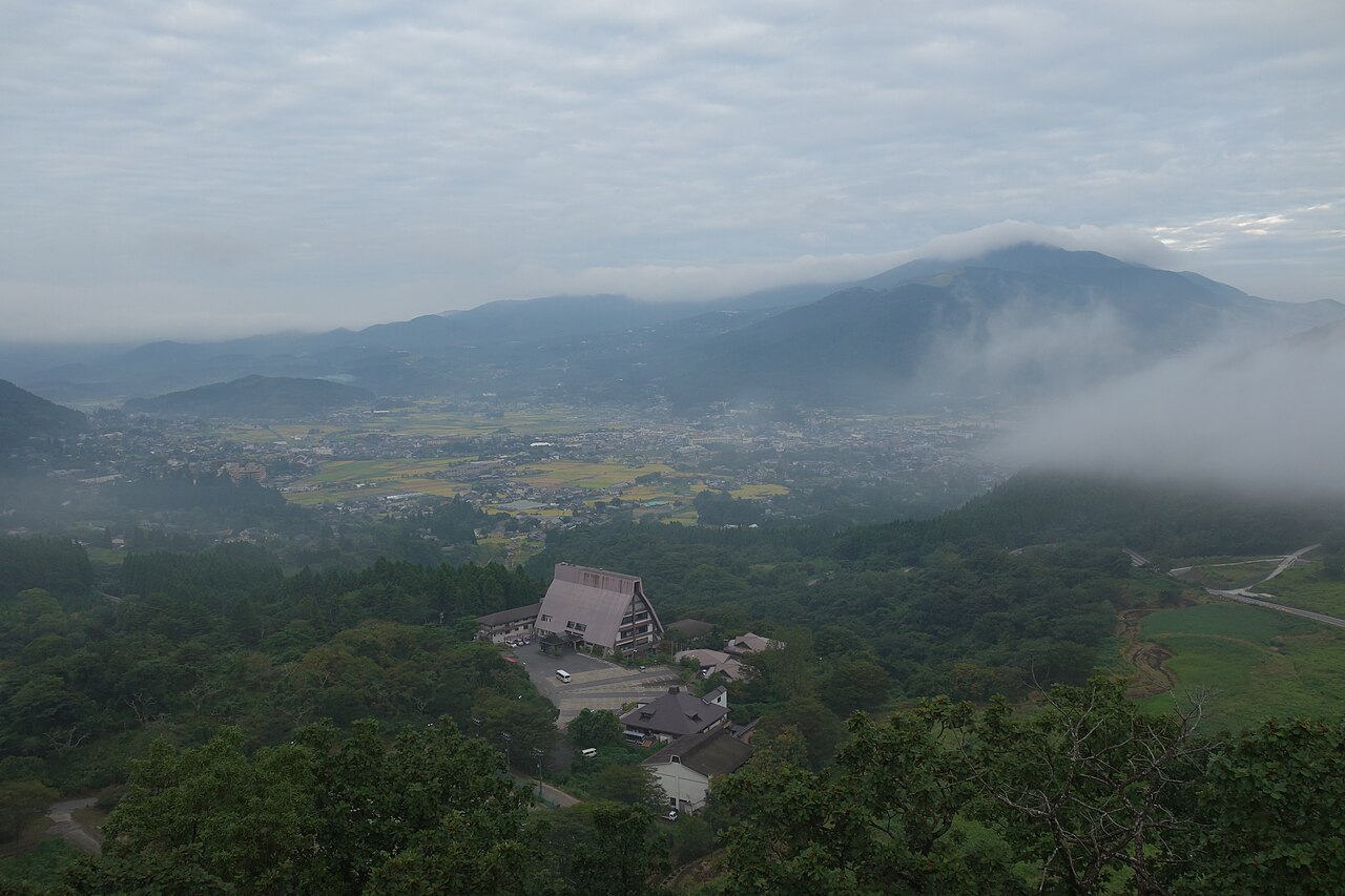 The Yufuin basin seen from Sagiridai, rice fields and rooftops under low cloud with mist rolling off the hills