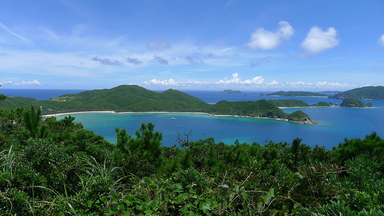 Looking down from a forested hillside on Zamami Island over a turquoise bay and the green islands of the Kerama group.