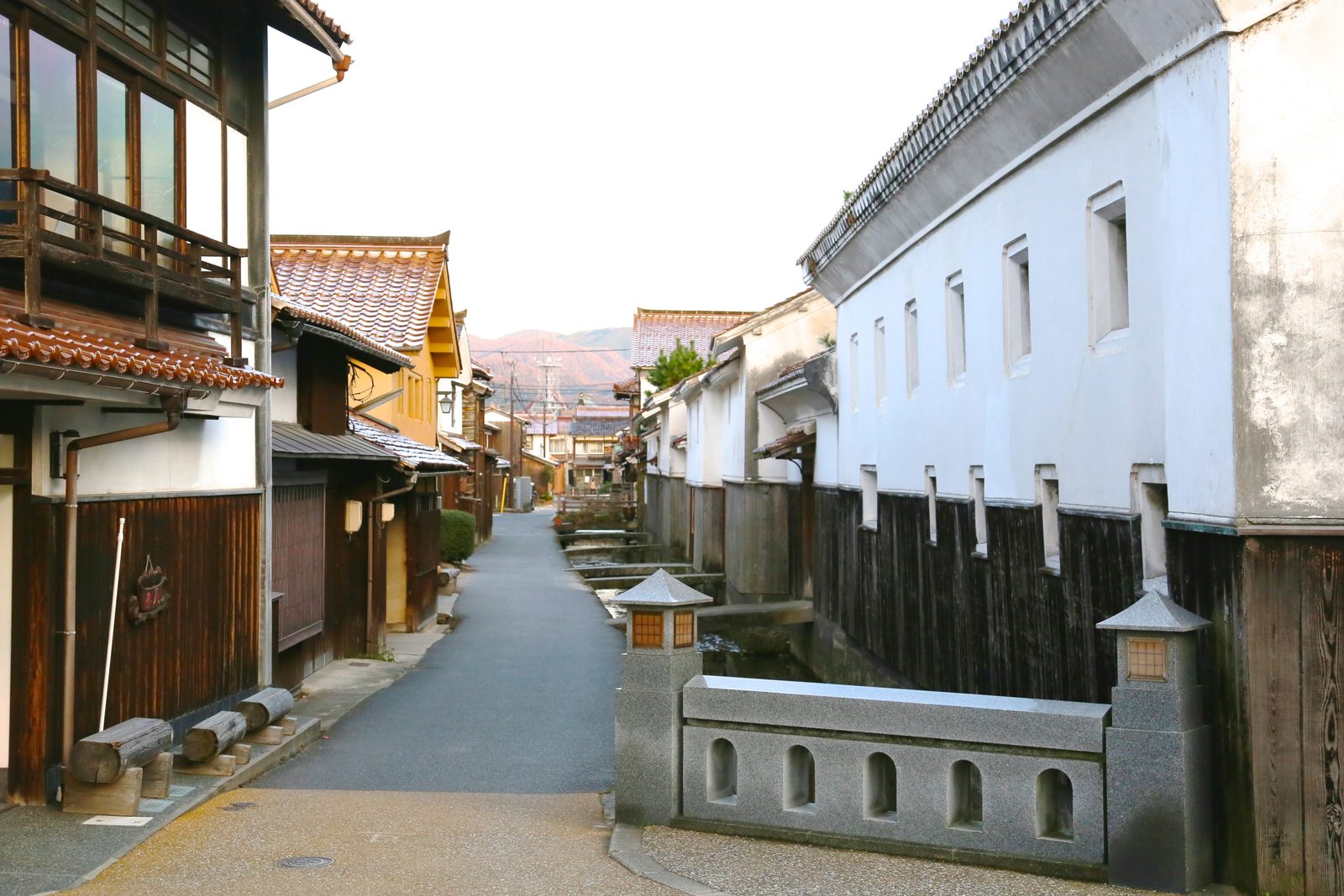 Evening light on the canal-side lane, white storehouses on the right and red-tiled townhouses on the left
