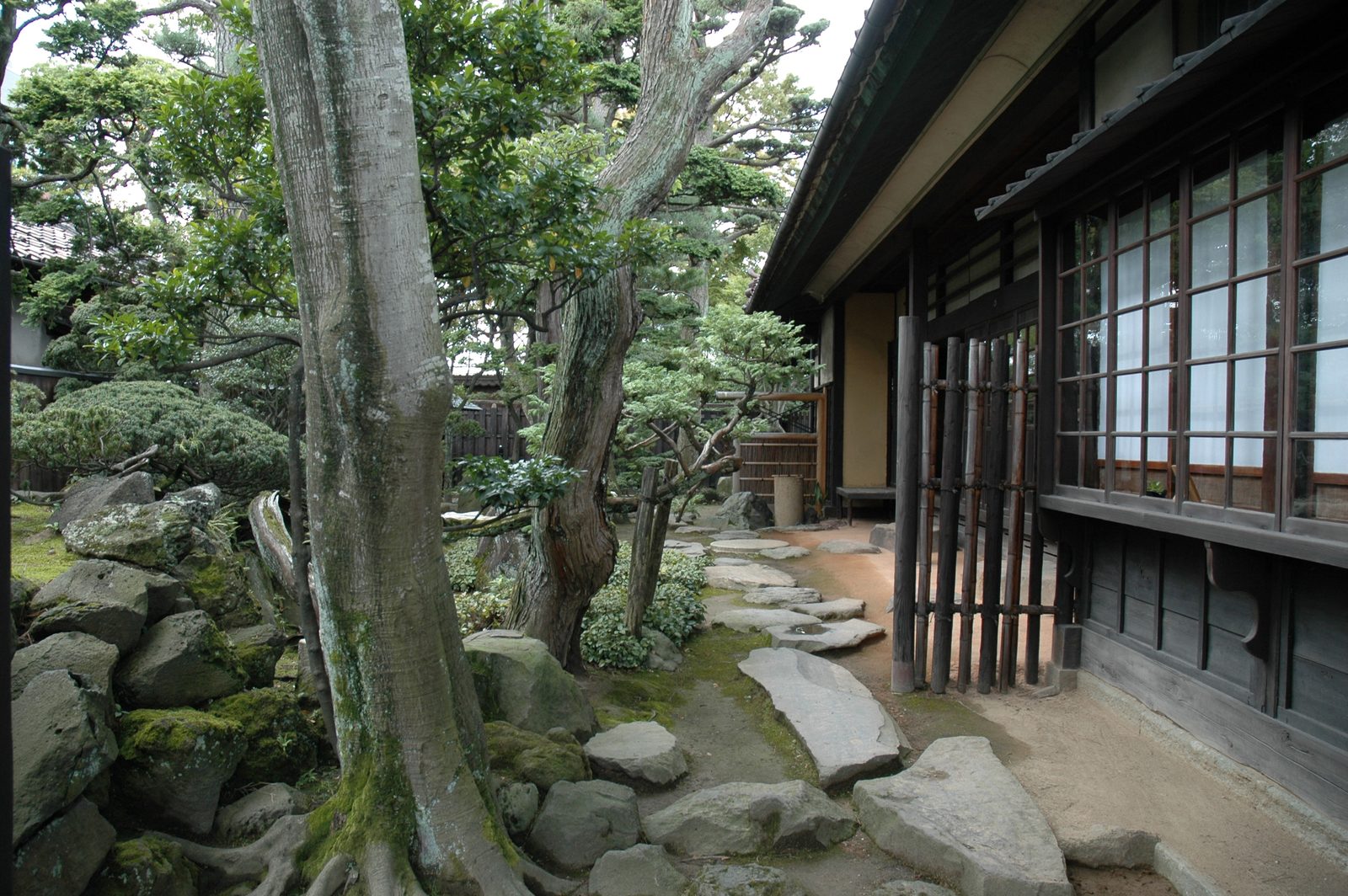 Garden of the former Homma family residence with a pine tree, stepping stones and the latticed doors of a veranda