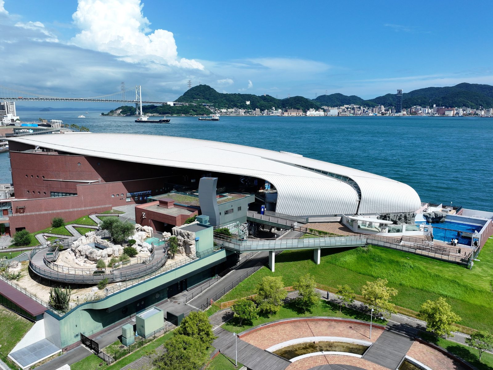 The curved white roof of the Kaikyokan aquarium beside the strait, seen from above