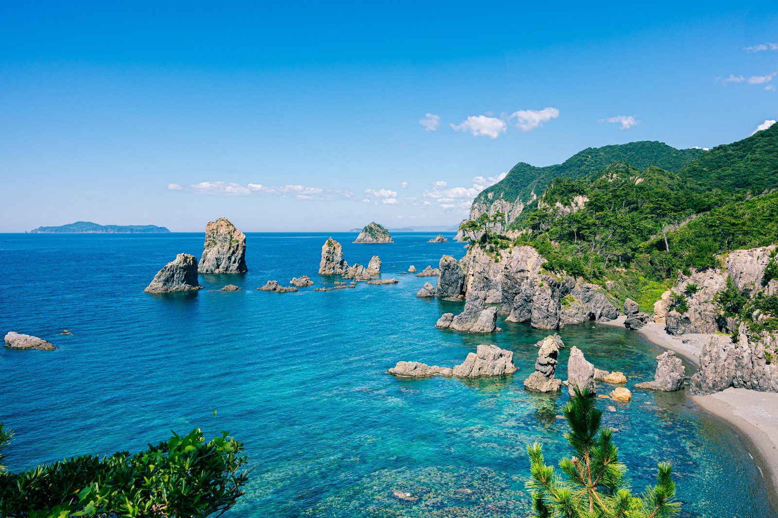 Rock stacks rising from clear blue water along the Omijima coast in Nagato