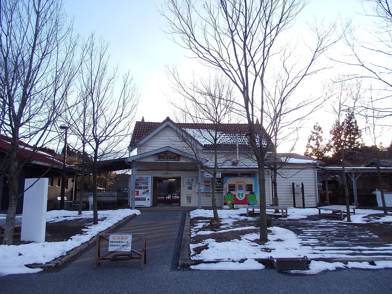 The small wooden station building at Yorokeikoku Station on a clear winter morning, with patches of snow on the ground.